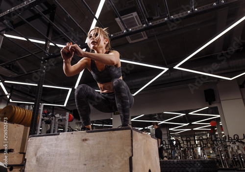 fit young ambitious blond woman doing a box jump exercise.hobby. side view full length photo. people concept photo