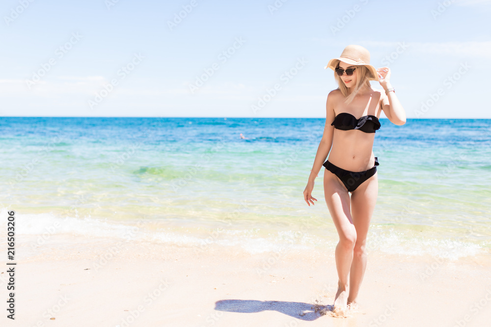 Happy smiling woman in bikini and sunhat on sea beach background Happy smiling woman in bikini and sunhat on sea beach background