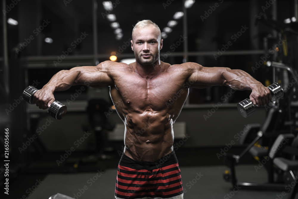 Handsome strong bodybuilder athletic men pumping up muscles with dumbbells Handsome strong bodybuilder athletic men pumping up muscles with dumbbells
