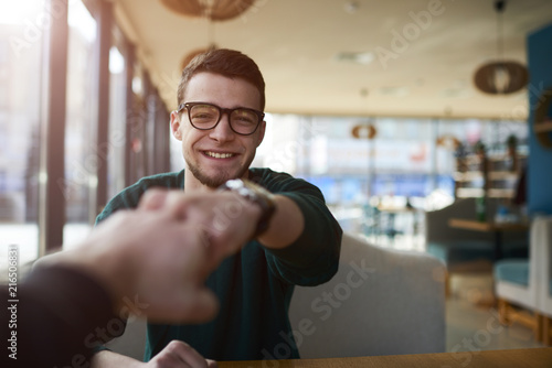 Cheerful young male colleagues IT developers high fiving during morning motivation meeting inspiring to good mood and hard working day using team building concept in coworking space photo