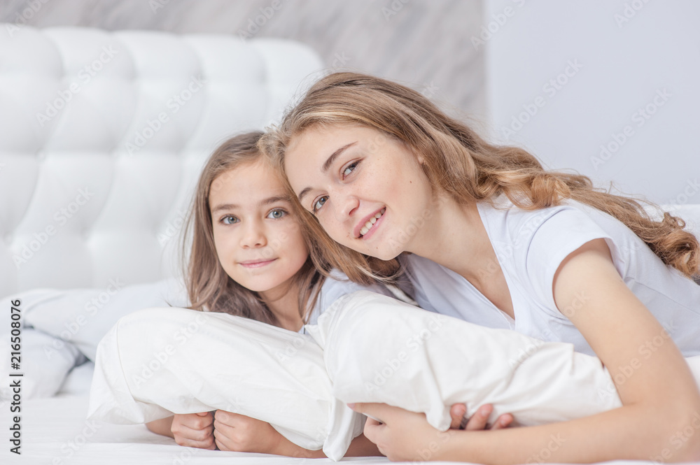 Happy sisters lying together on the bed