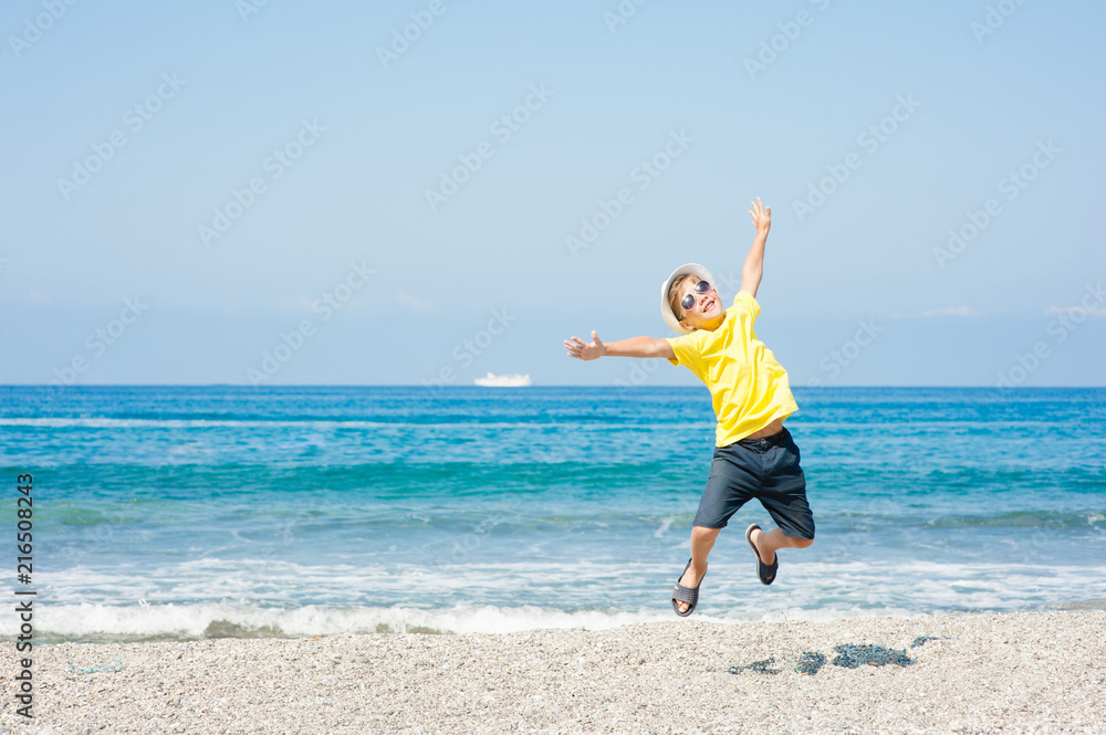 Happy boy jumping on the beach. Travel concept. Space for text Happy boy jumping on the beach. Travel concept. Space for text