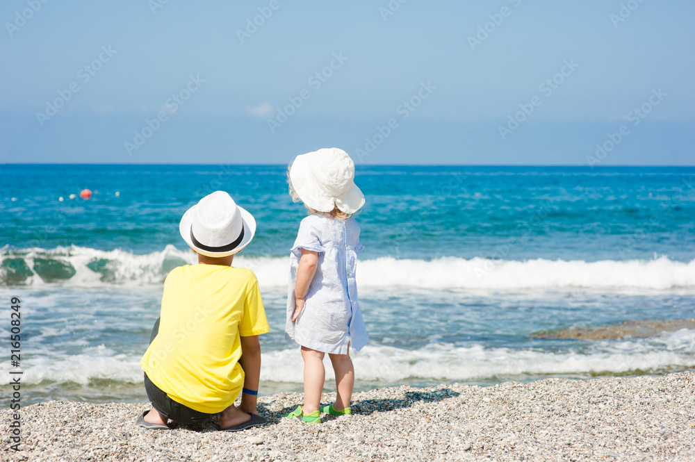 Boy and baby girl on the beach on summer holidays. concept of summer family vacation. Space for text Boy and baby girl on the beach on summer holidays. concept of summer family vacation. Space for text
