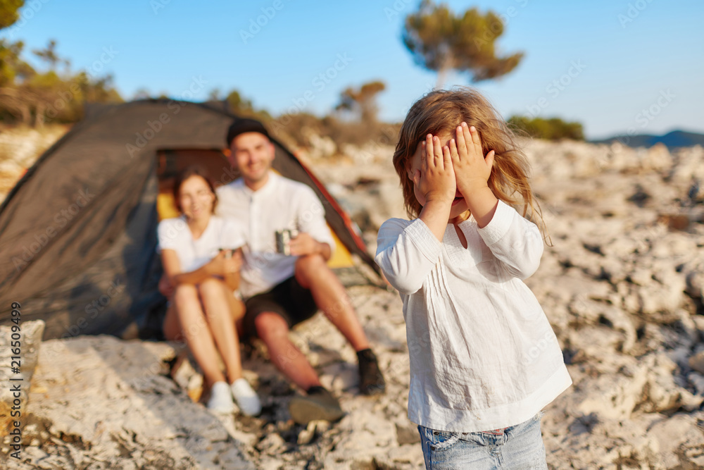 Pretty girl standing on rocky beach and closing eyes covering face with hand. Pretty girl standing on rocky beach and closing eyes covering face with hand.