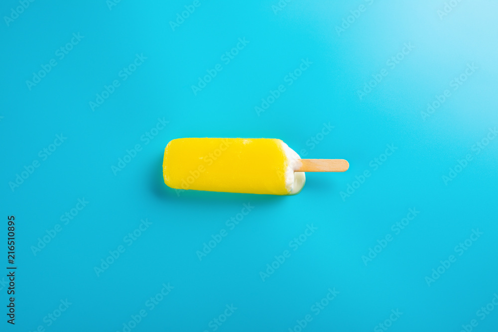 yellow popsicle starts melting on blue background yellow popsicle starts melting on blue background