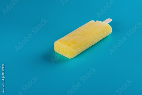 side view yellow popsicle on a blue background