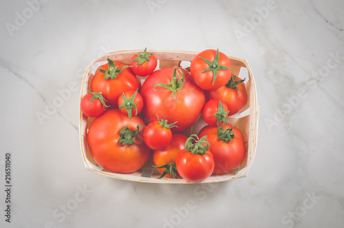 tomatoes in a wattled basket/tomatoes in a wattled basket on a white marble background. Top view