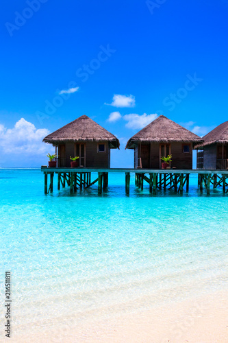 Fototapeta Naklejka Na Ścianę i Meble -  Water villas on wooden pier in turquoise ocean on the white sand beach