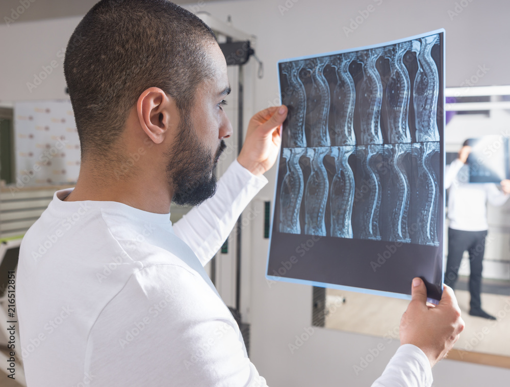 Physiotherapist Looking at X-Ray Film of Spine