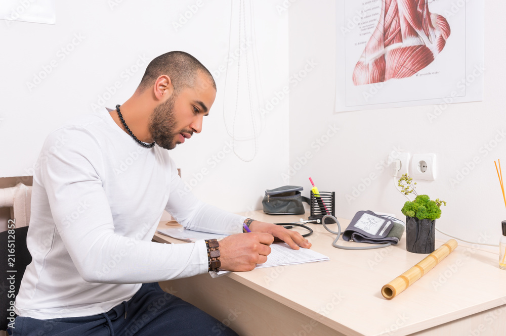 Man sitting at a desk writing notes in an office Man sitting at a desk writing notes in an office