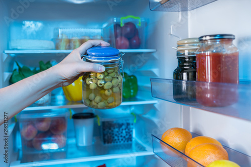 Obraz na płótnie Hand reaching for jar with olives in fridge w salonie