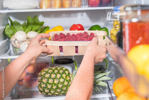 Person taking basket with fruits from fridge