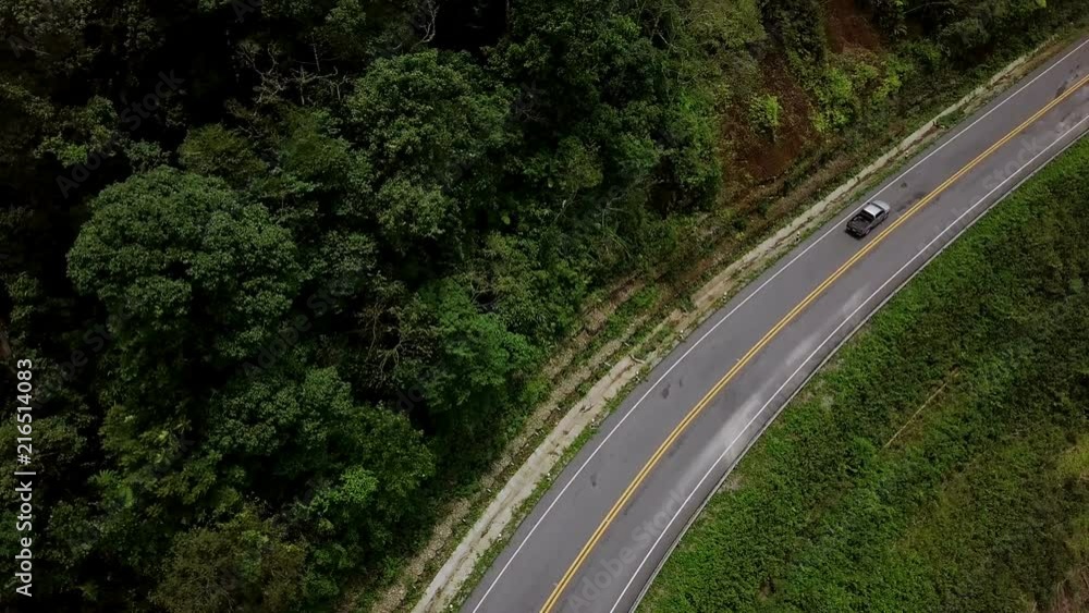 Aerial view of a pick up truck driving on the countryside road surrounded by the beautiful Doi Phuka mountain forrest in Nan Province Northern Thailand Aerial view of a pick up truck driving on the countryside road surrounded by the beautiful Doi Phuka mountain forrest in Nan Province Northern Thailand