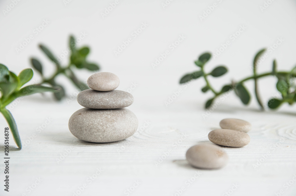 Pyramids of white zen stones with green leaves on white background. Concept of harmony, balance and meditation, spa, massage, relax Pyramids of white zen stones with green leaves on white background. Concept of harmony, balance and meditation, spa, massage, relax
