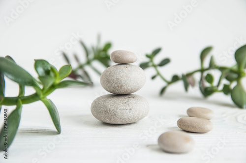 Pyramids of white zen stones with green leaves on white background. Concept of harmony, balance and meditation, spa, massage, relax