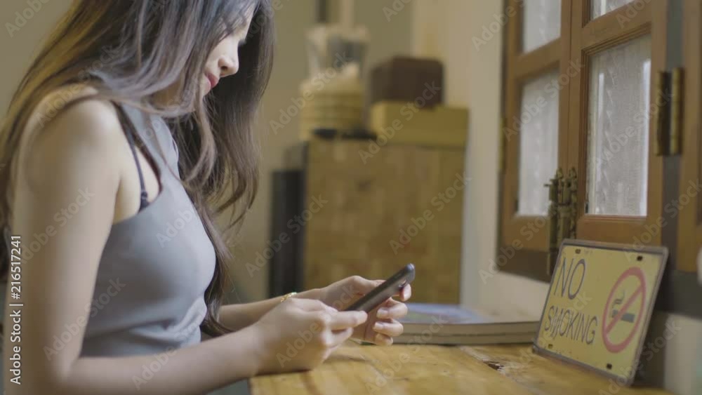 Asian women check their mobile phones happily at coffee shops.