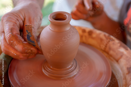 The master's hands make a pot on the potter's wheel.