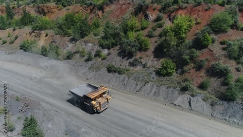 A large mining dump truck is moving along the roads of the quarry. Shooting from a quadrocopter. Shooting from the drone