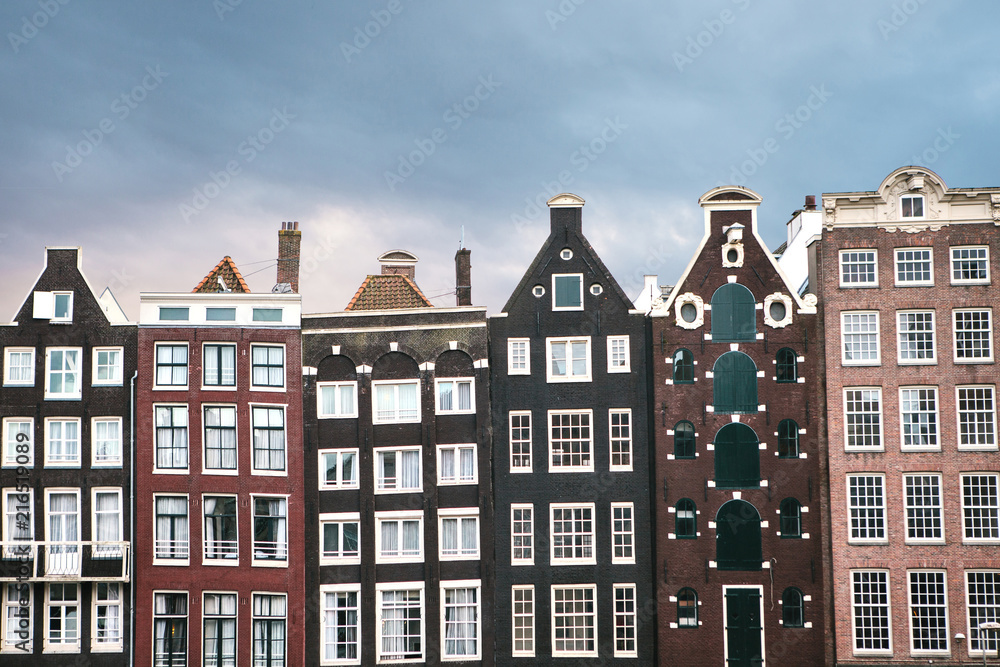 Traditional houses in Amsterdam in the Netherlands in a row against the backdrop of the setting sun.