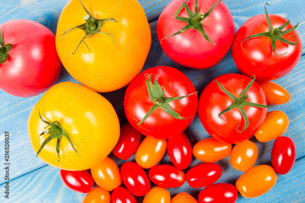 Different varieties of tomatoes on a blue wooden background. Different varieties of tomatoes on a blue wooden background.