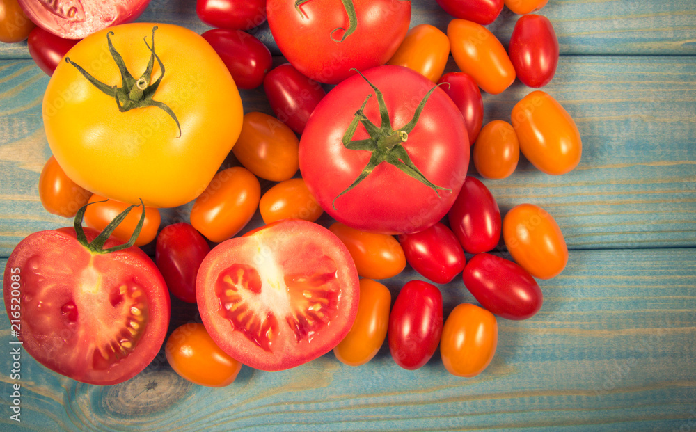 Different varieties of tomatoes on a blue wooden background. Different varieties of tomatoes on a blue wooden background.