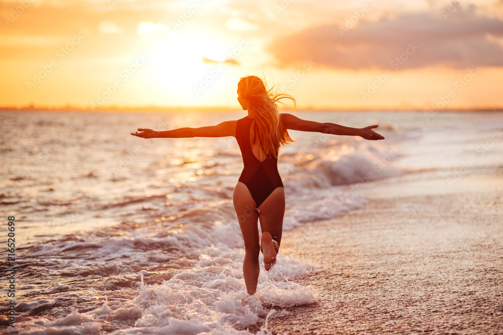 carefree woman dancing in the sunset on the beach.