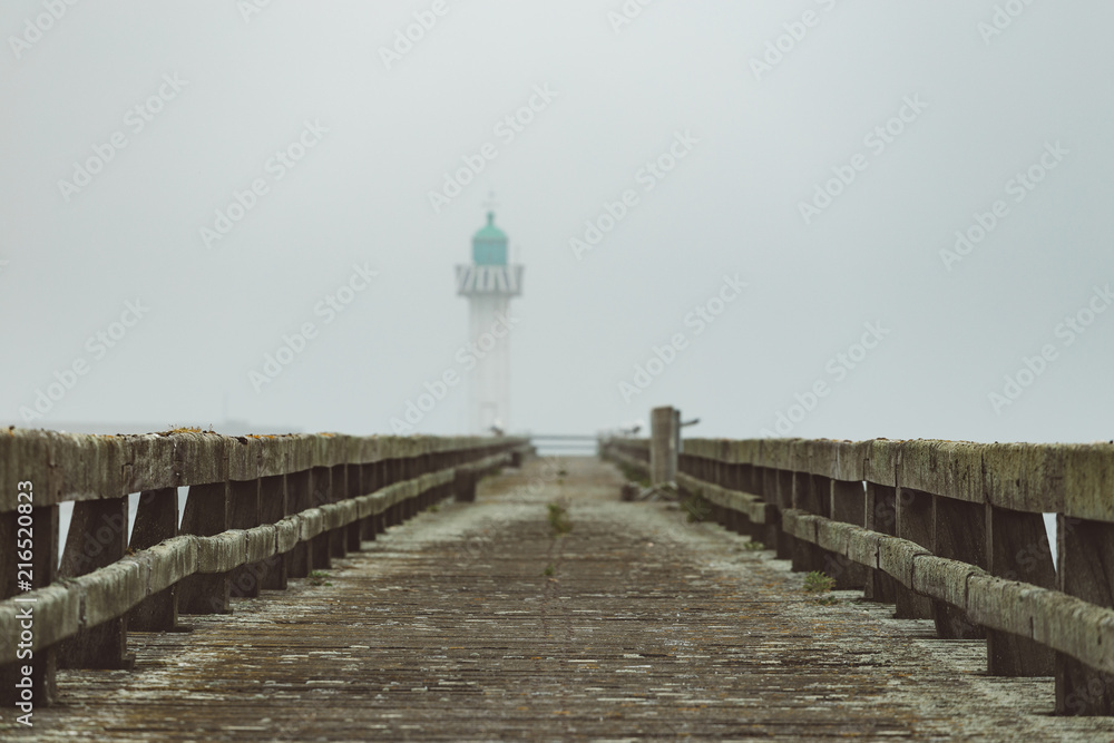 Pier and lighthouse in the harbour of Deauville on a misty morning in Normandy, France. English channel seascape Pier and lighthouse in the harbour of Deauville on a misty morning in Normandy, France. English channel seascape