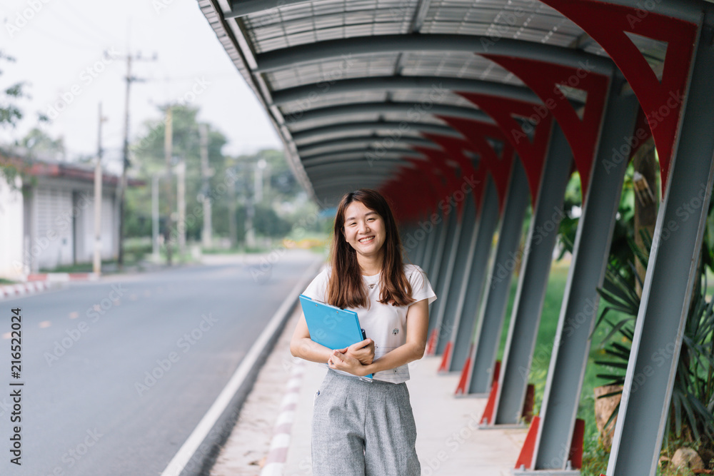 Young woman university student holding her books smiling happily standing on the doorstep of her classroom.