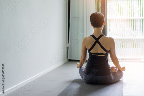 Fototapeta Naklejka Na Ścianę i Meble -  Young woman practicing yoga in  gray background.Young people do yoga indoor.Close up hands in meditating gesture. Copy space.