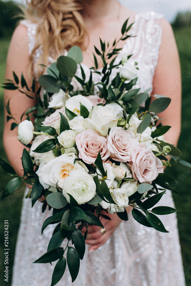 Naklejka premium Bride in white wedding dress with a beautiful bouquet of roses
