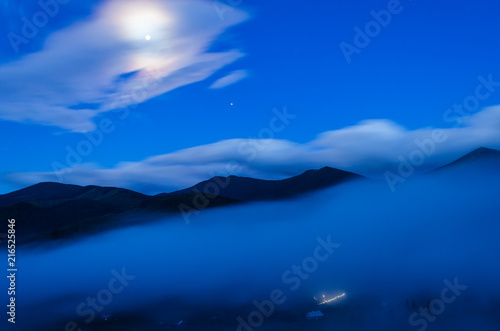 silhouette of mountains in foggy weather against a blue sky