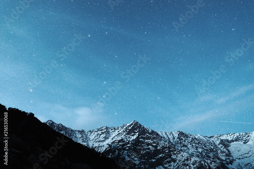 Snowy mountains of north India against the background of stars on a blue night sky. Natural landscape