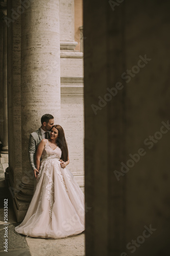 Young newly married couple posing in Rome with beautiful and ancient architecture in the background