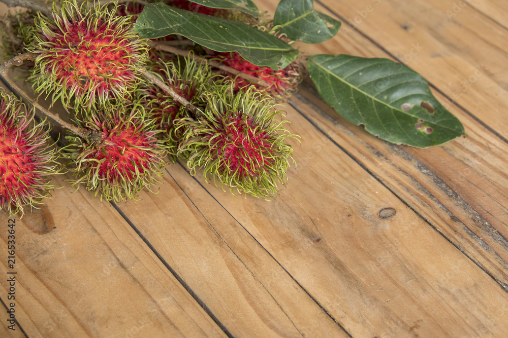 Red rambutan Nephelium lappaceum on broun board. Fruit tropical tree of the family Sapindaceae , native to South - East Asia , cultivated in many countries in the region Red rambutan Nephelium lappaceum on broun board. Fruit tropical tree of the family Sapindaceae , native to South - East Asia , cultivated in many countries in the region