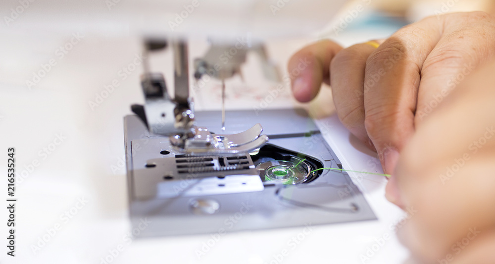 Close up - Female tailor working with sewing machine..Profestional woman hands during sewing work with yarn on sewing machine. Close up - Female tailor working with sewing machine..Profestional woman hands during sewing work with yarn on sewing machine.
