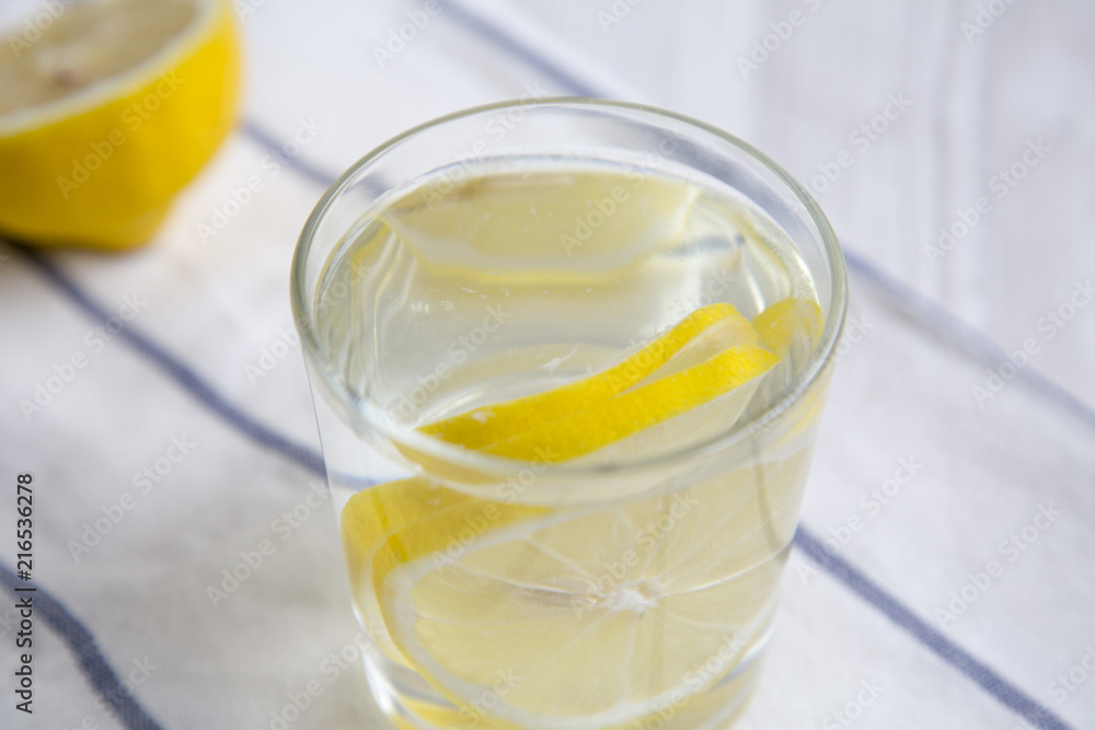 Water with lemon in glass on striped napkin. Diet weight loss and healthy eating. Detox drink. Water with lemon in glass on striped napkin. Diet weight loss and healthy eating. Detox drink.