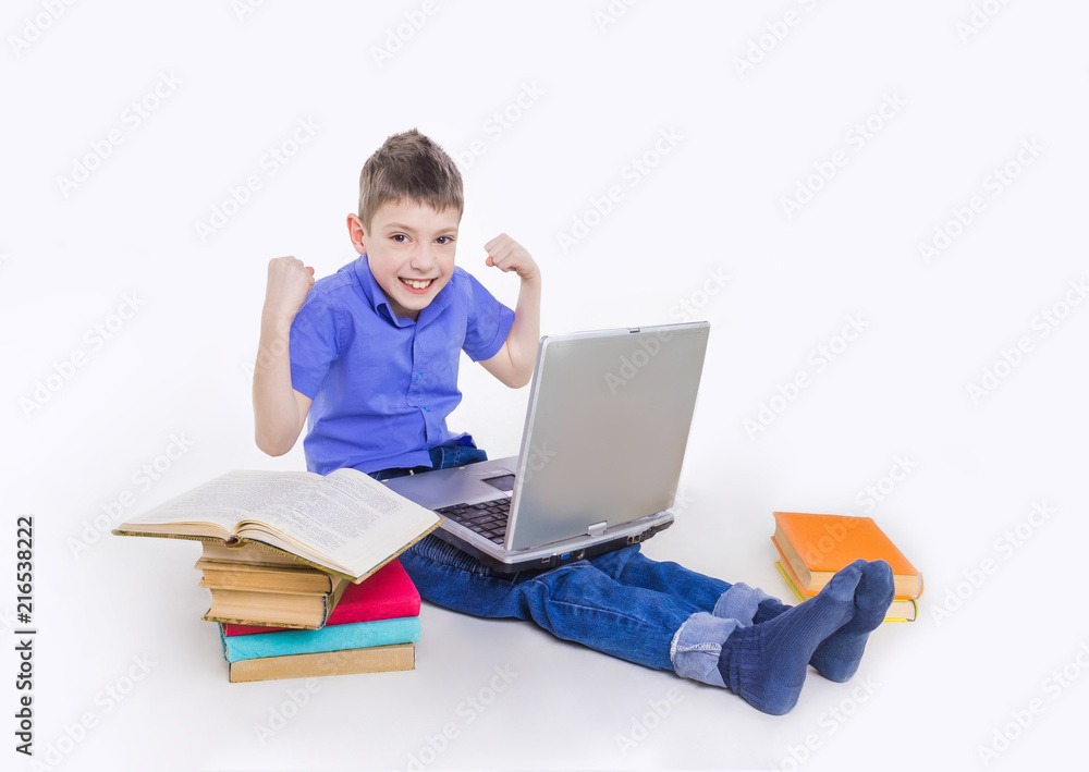 Portrait of cute schoolboy sitting with books and typing on laptop keyboard Portrait of cute schoolboy sitting with books and typing on laptop keyboard