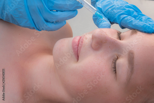 Portrait of a teenage girl doing an injection of botox hyaluronic acid in the skin near the eyes close up