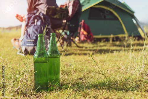 Close up of beer bottle in meadow while camping at outdoors. Holiday and Vacation concept. Adventure and outdoors theme.