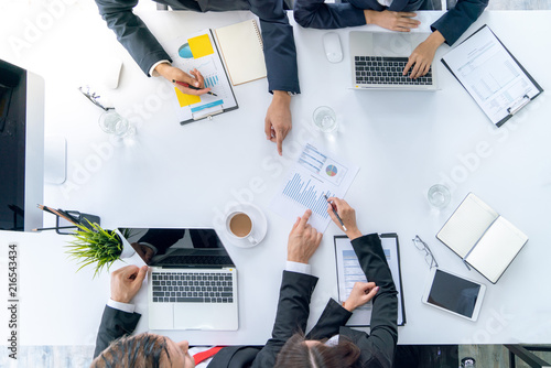 Top view hand of business team during meeting conference are working documents about the marketing plan and sales profit finance of the company with laptop computer and smartphone tablet on work table