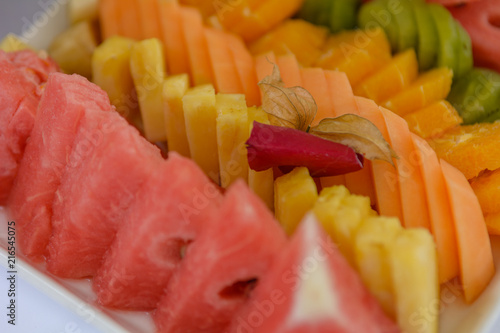 Watermelon slices in front of colourful fruit background