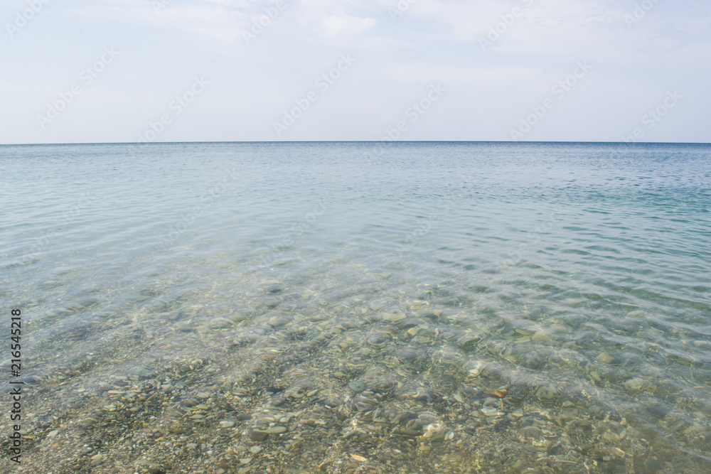 Clear and quiet sea water with stones and blue sky with clouds. Clear and quiet sea water with stones and blue sky with clouds.