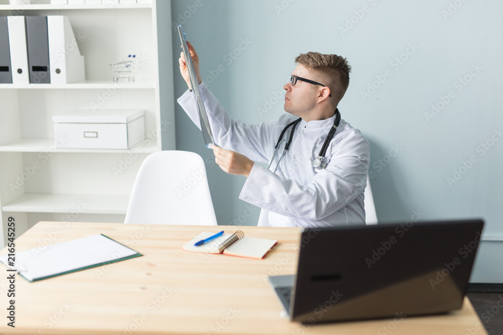 Portrait of a young doctor checking x-ray image in office