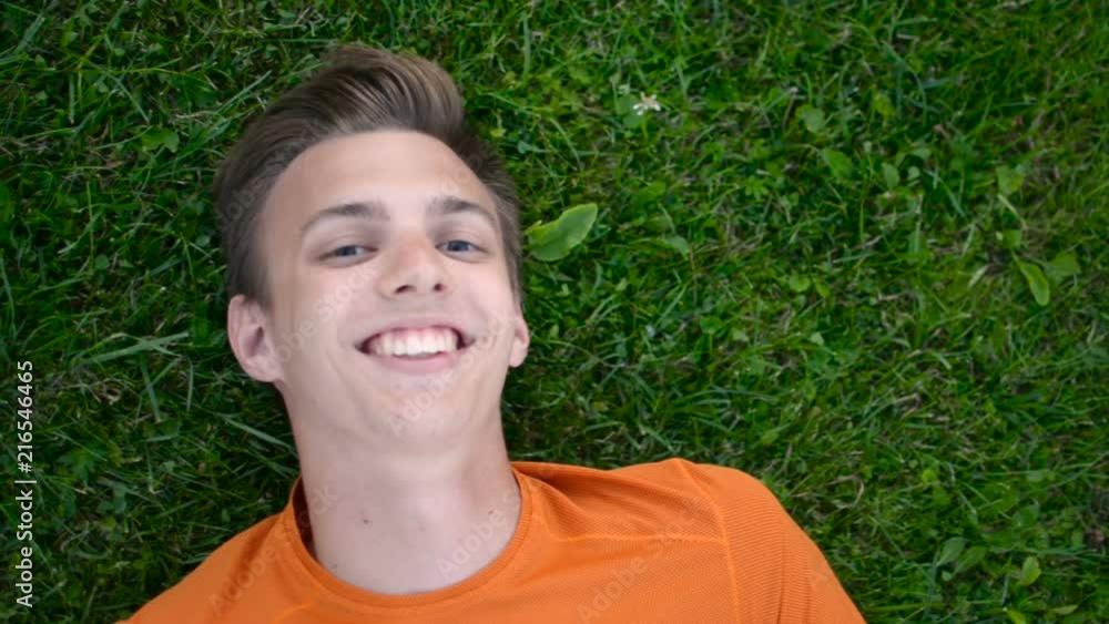 Boy makes weird funny facial expression to camera laying on the ground Boy makes weird funny facial expression to camera laying on the ground