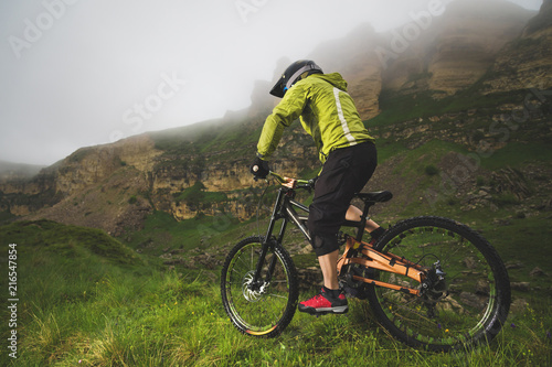 A man in a mountain helmet riding a mountain bike rides around the beautiful nature in cloudy weather. downhill