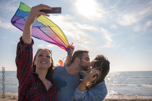 Group of friends making selfie on beach during autumn day