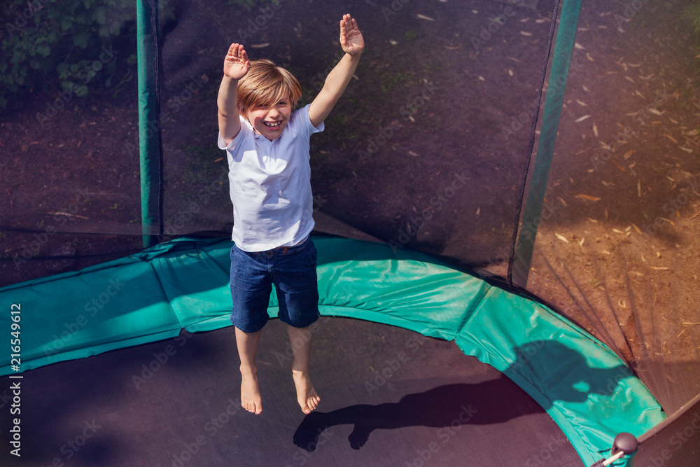 Excited boy bouncing on the trampoline outdoors