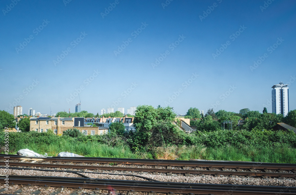 Fototapeta premium View of London suburbs from the in motion train - houses, fields, skyscrapers