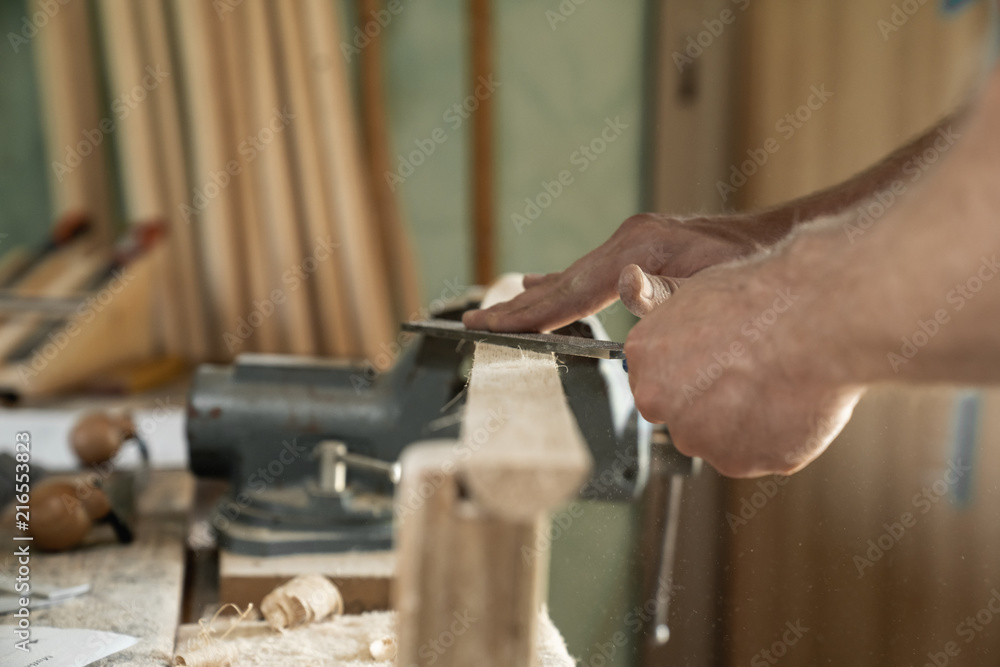 Mann arbeitet mit einer Raspel auf Holzwerkstück in einer Werkstatt