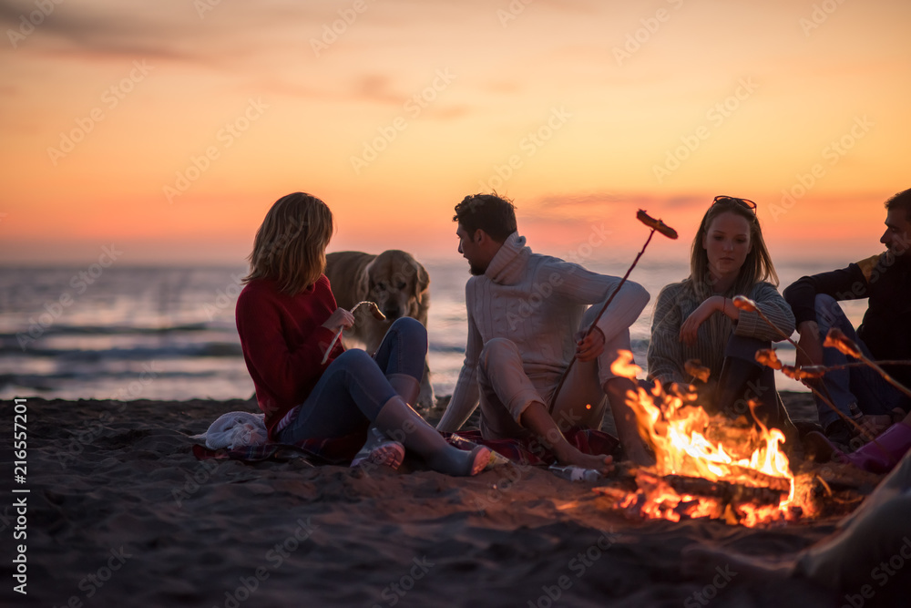 Group Of Young Friends Sitting By The Fire at beach Group Of Young Friends Sitting By The Fire at beach